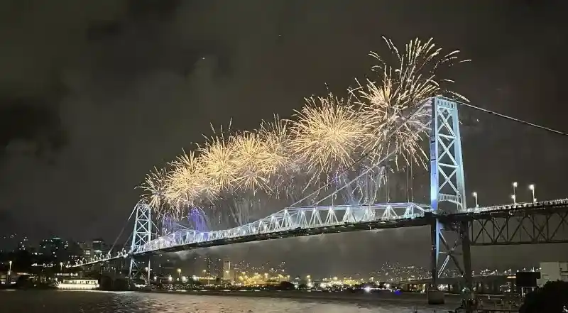 Ponte pênsil de ferro iluminada pelos fogos de artifício em Florianópolis, um dos melhores lugares para passar o réveillon